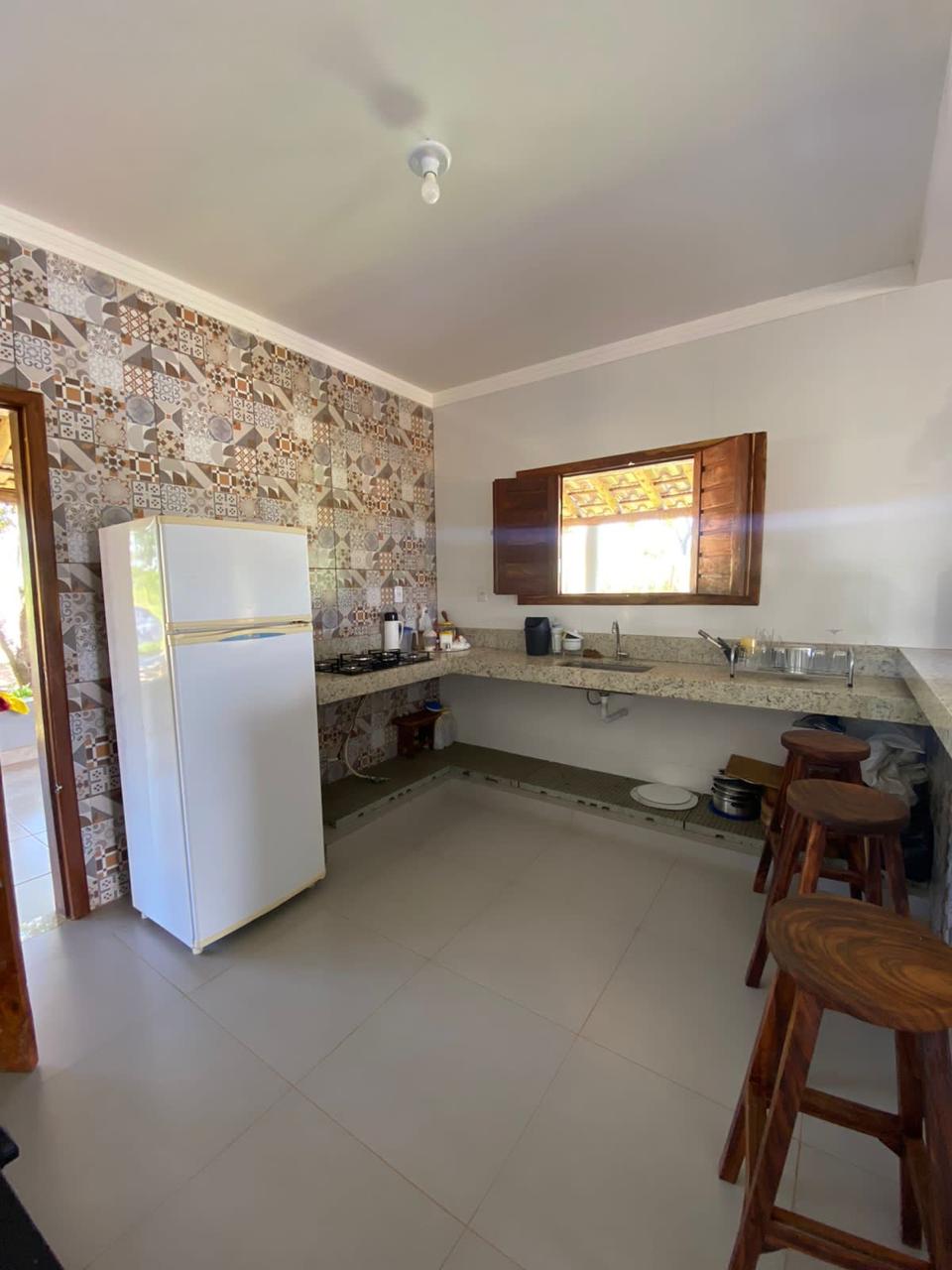 Cozinha de apoio com geladeira e banquetas