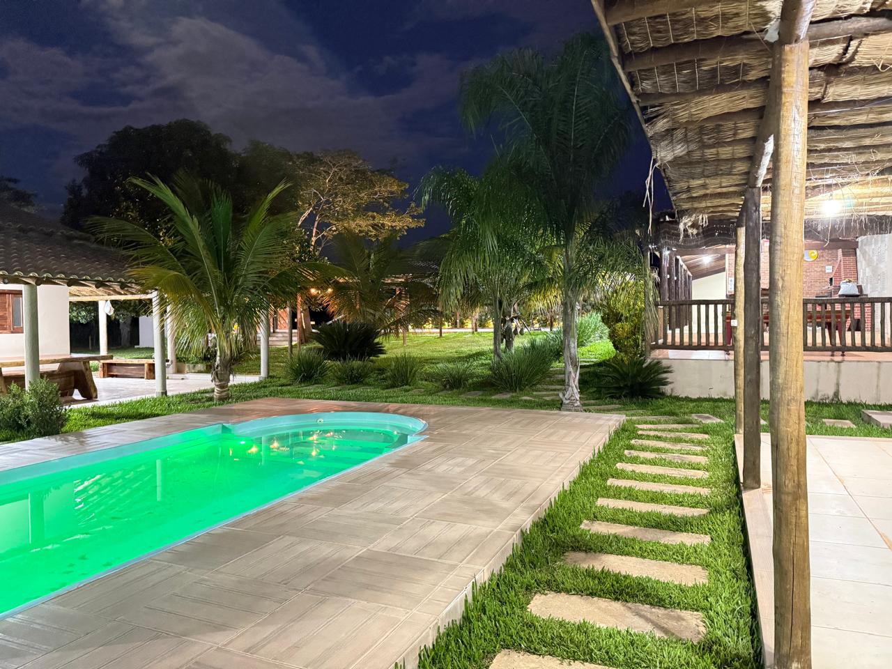 Piscina entre coqueiros ao anoitecer
