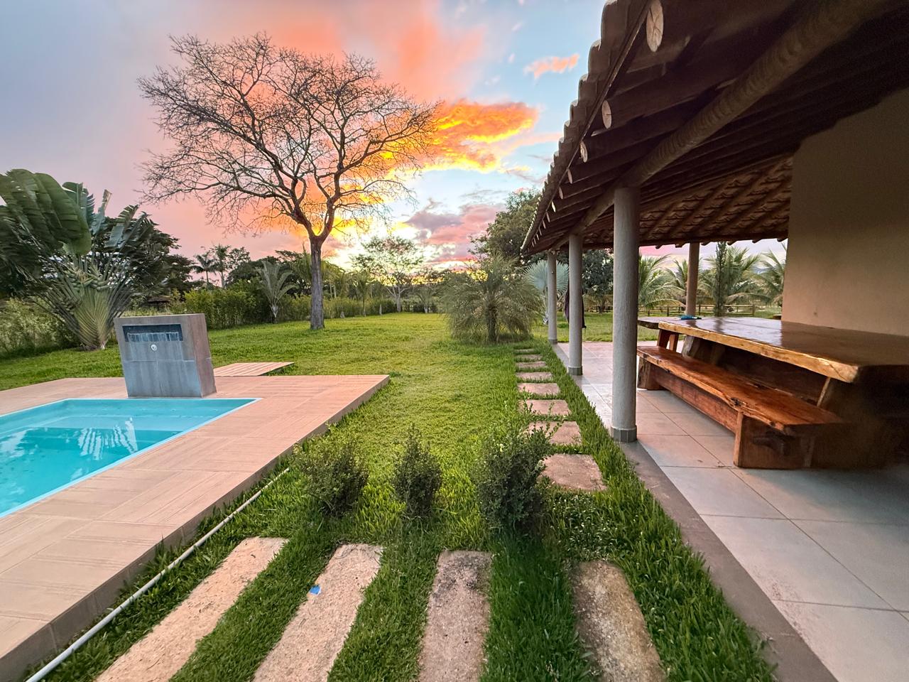 Piscina e quiosque com mesa de madeira ao entardecer